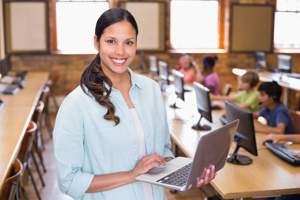 Pretty teacher using laptop in computer class at the elementary school